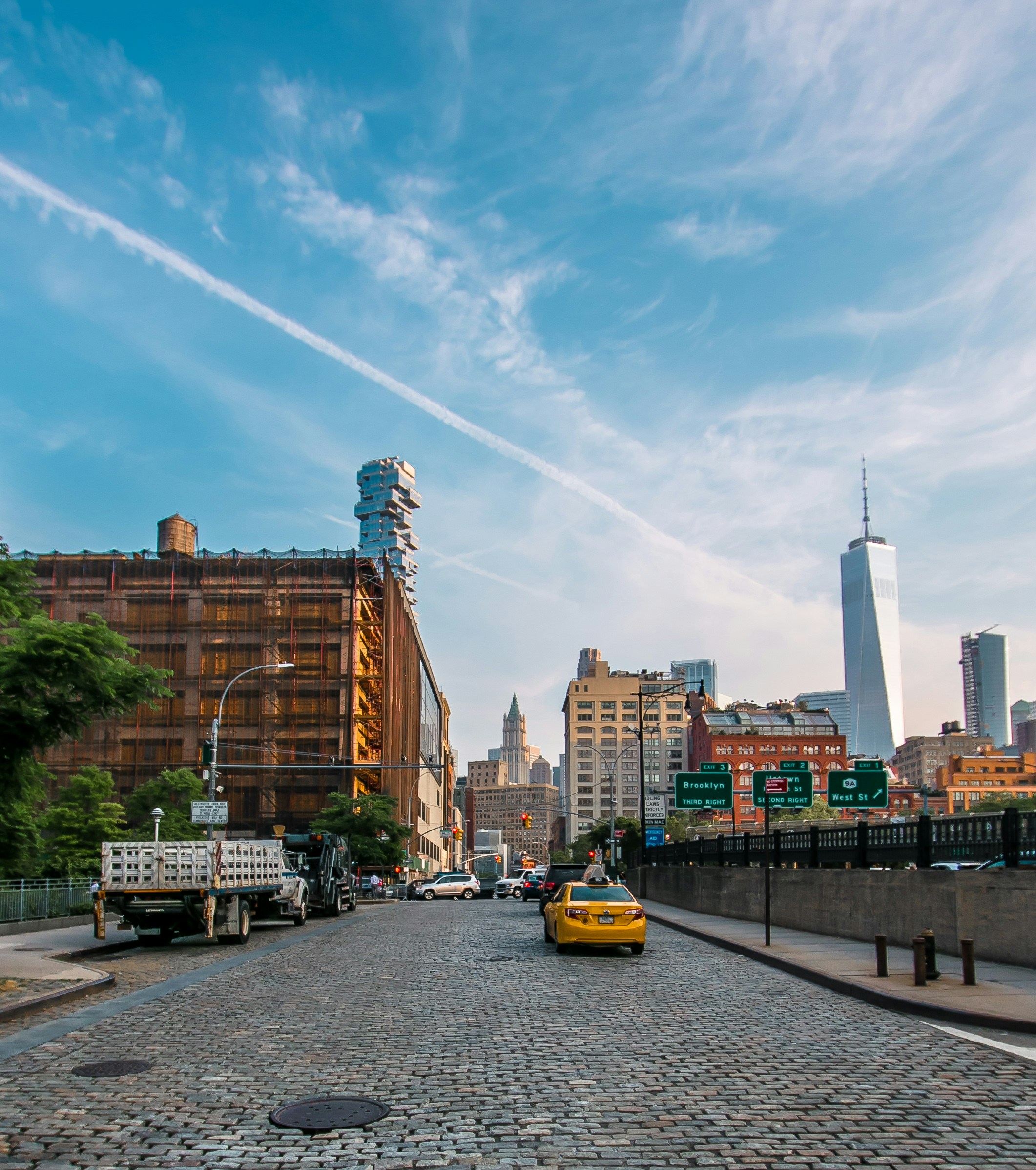A cobblestone Tribeca street with an old loft warehouse, 56 Leonard and One World Trade in the distance